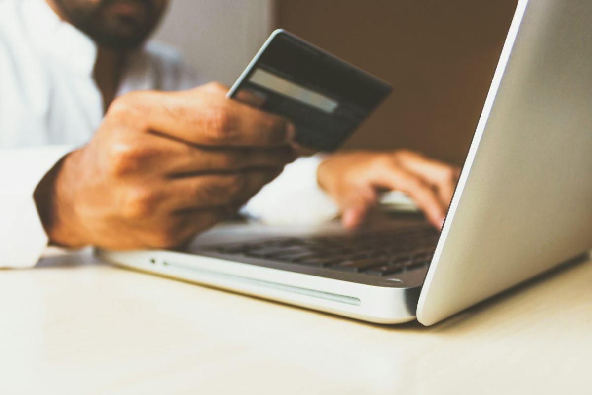 Un uomo con una carta di credito mentre fa un acquisto online