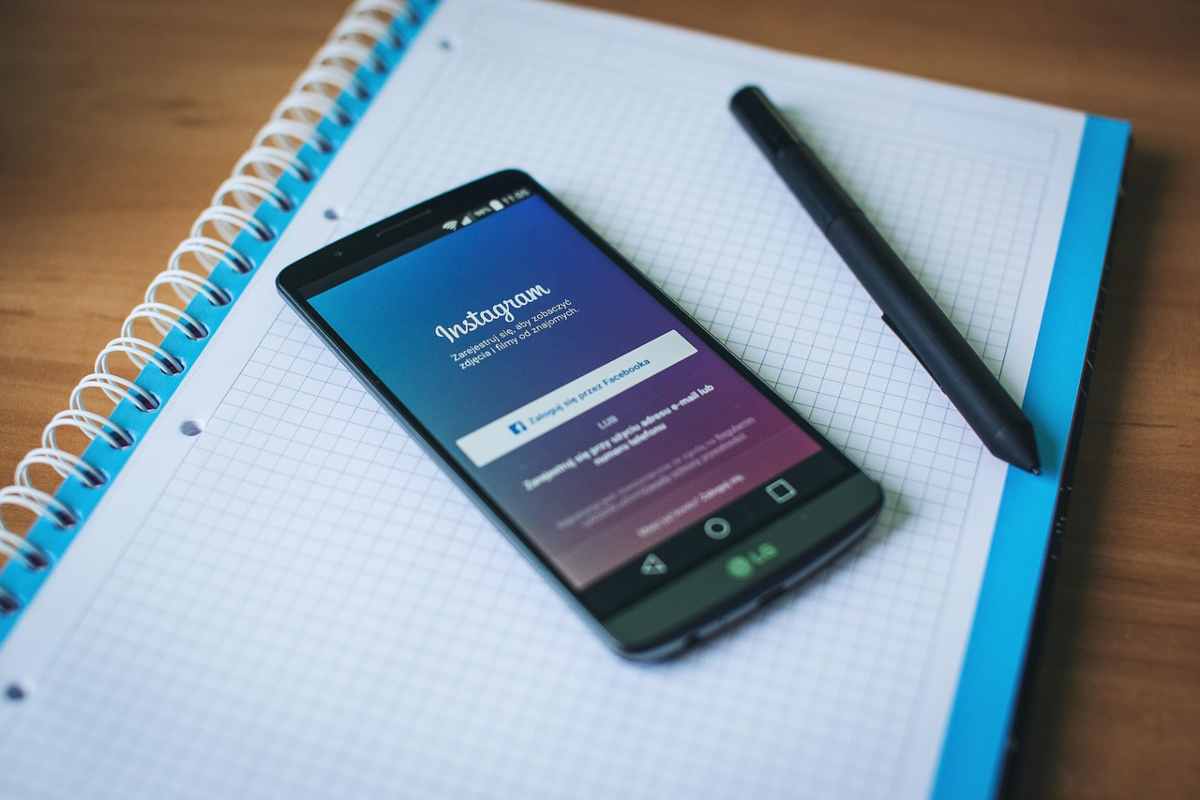 Uno smartphone su Instagram poggiato su un quaderno con una penna