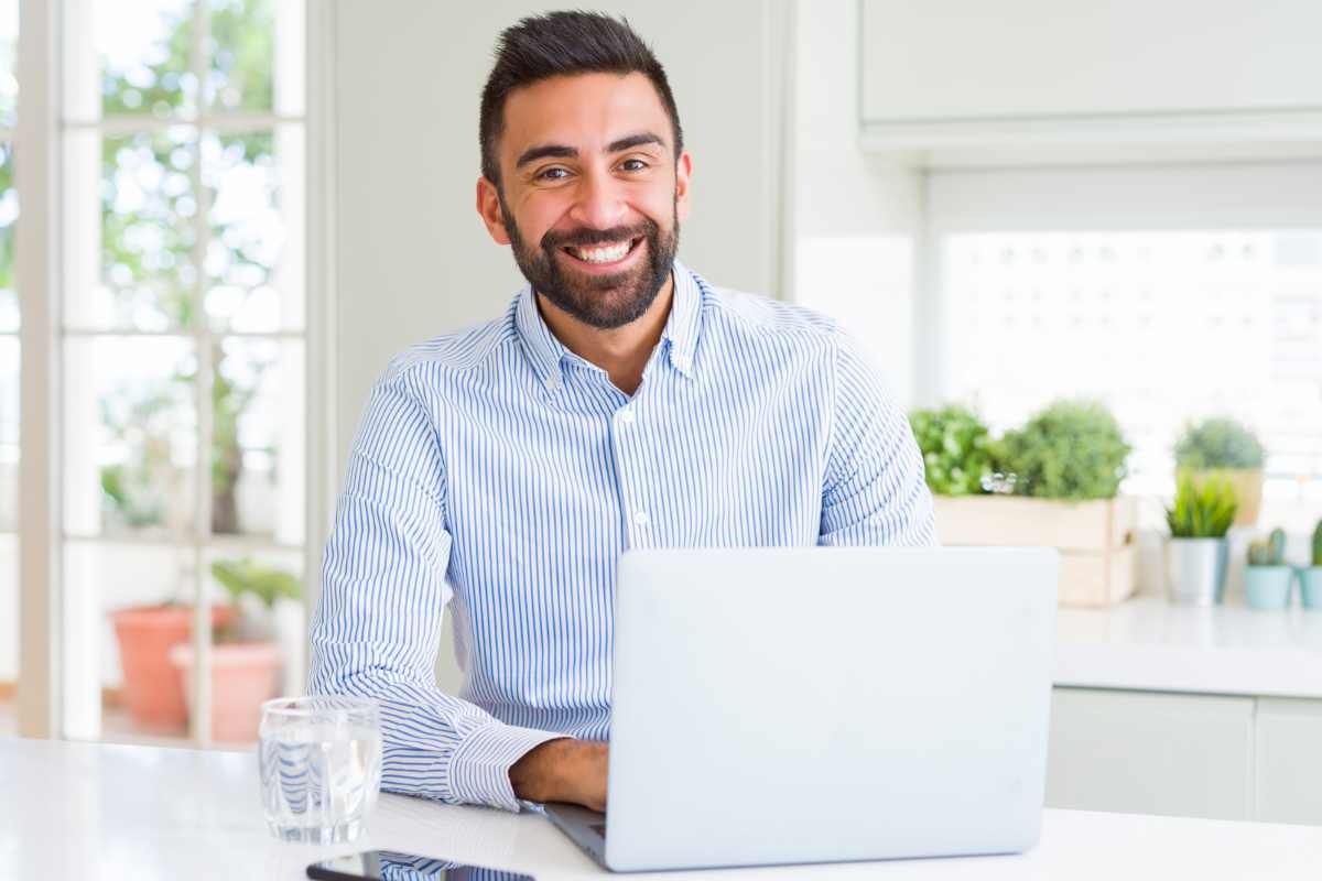 uomo sorridente davanti al suo computer portatile