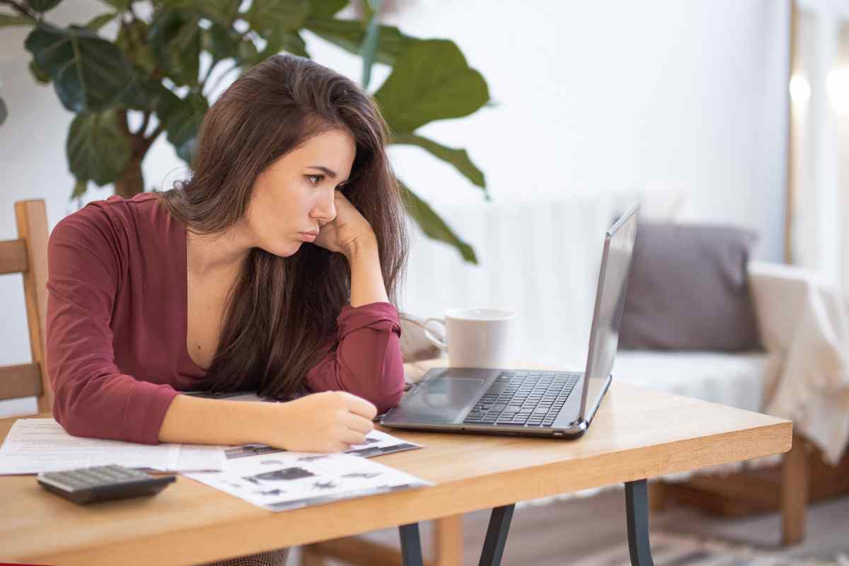 donna guarda lo schermo di un pc portatile che ci mette tanto ad accendersi
