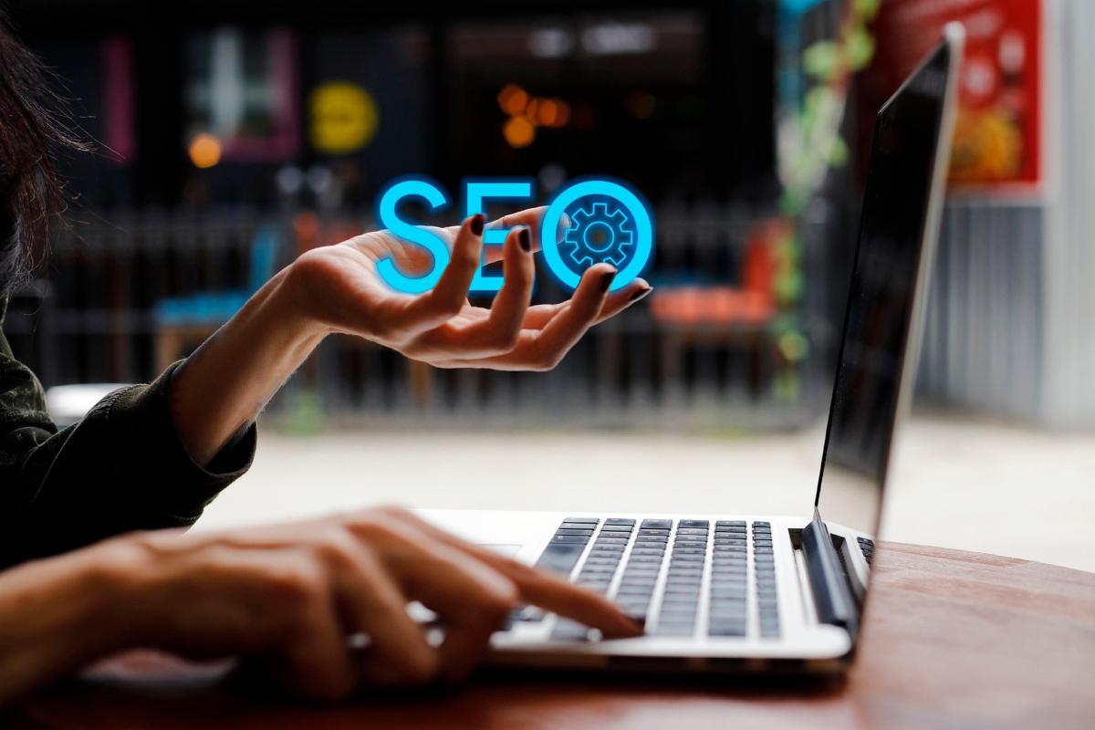 Scritta SEO in una mano davanti a un laptop