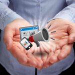 megafono, smartphone e computer tra due mani