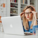 Persona con le mani in testa davanti a un laptop